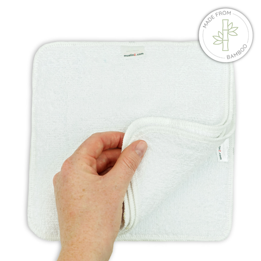 White bamboo towel being held by a hand with a 'Made from Bamboo' label in the corner.