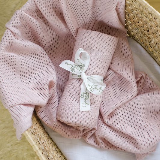 Pink textured blanket with a tag in a wicker basket