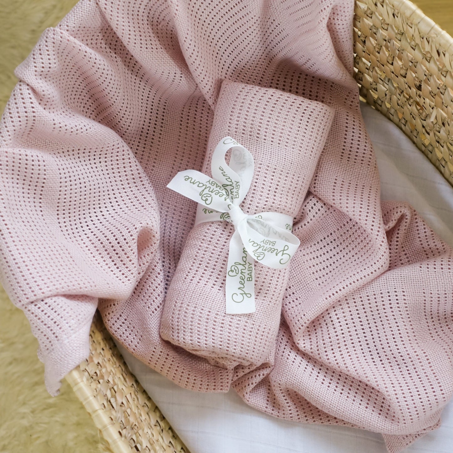 Pink textured blanket with a tag in a wicker basket