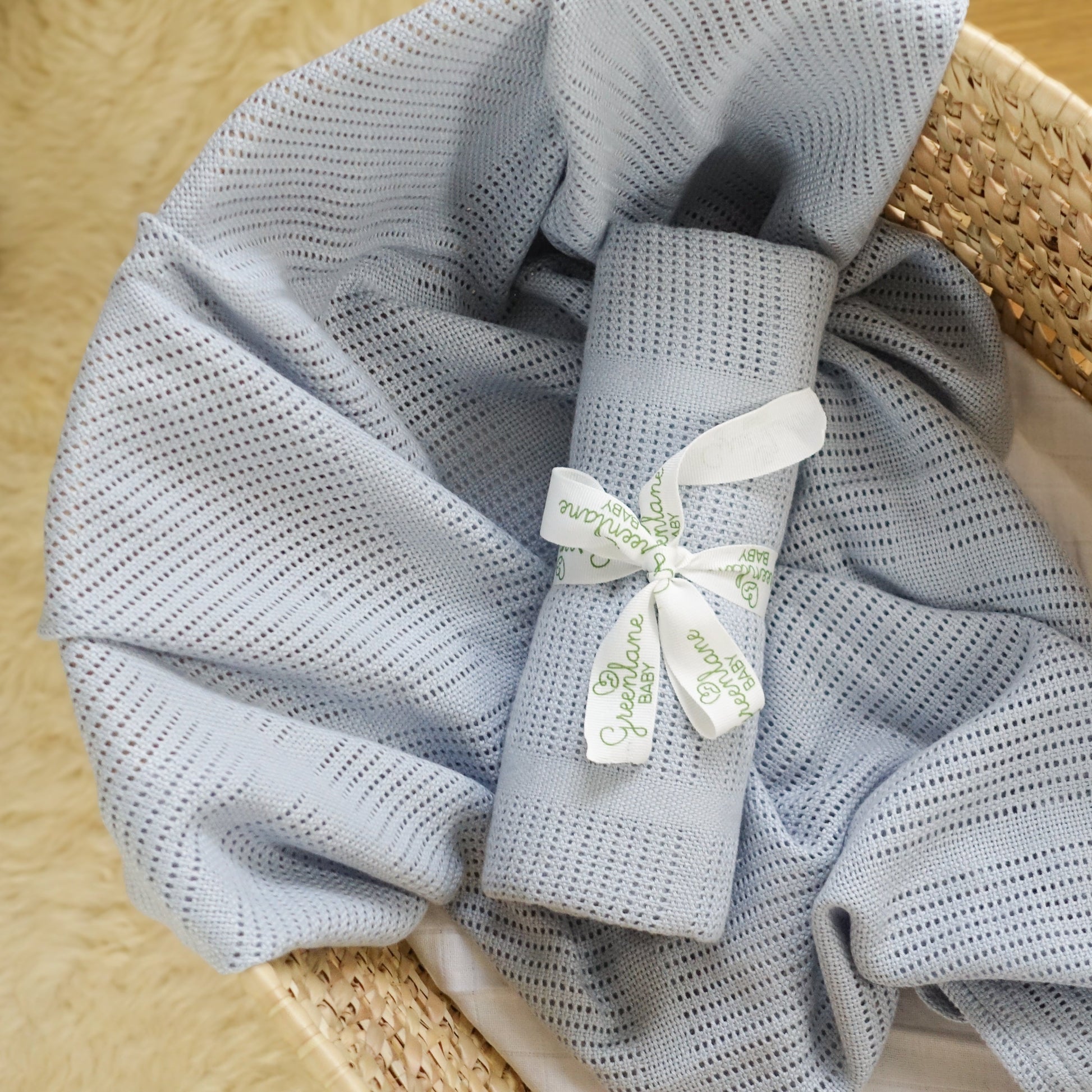 Rolled-up gray towel with a white ribbon and tag on a woven surface