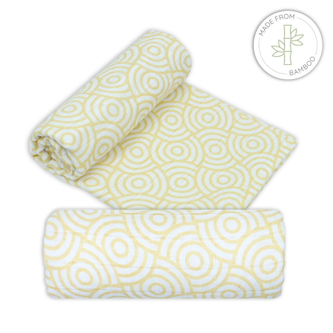 Muslin bamboo swaddles with gold swirl pattern print on a white background for babies
