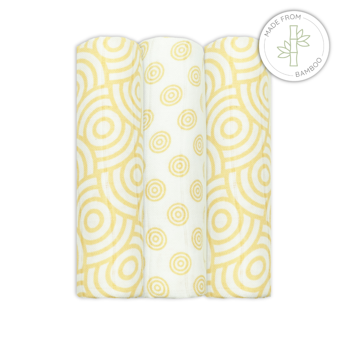 Three bamboo muslins swaddles with yellow circular pattern on a white background
