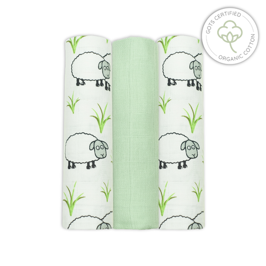 Three swaddle blankets with sheep and grass pattern on a white background, featuring an Organic Cotton certification logo.
