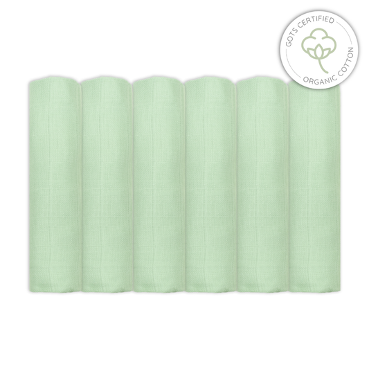 Stack of light sage green baby muslin swaddles with Organic Cotton certification logo on a white background