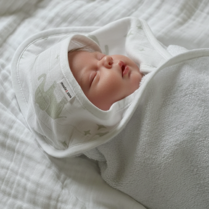 Newborn baby swaddled in white hooded towel with 'Zara' label