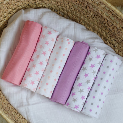 Set of folded fabric swatches with star and polka dot patterns in pink, white, and purple on a woven basket background.