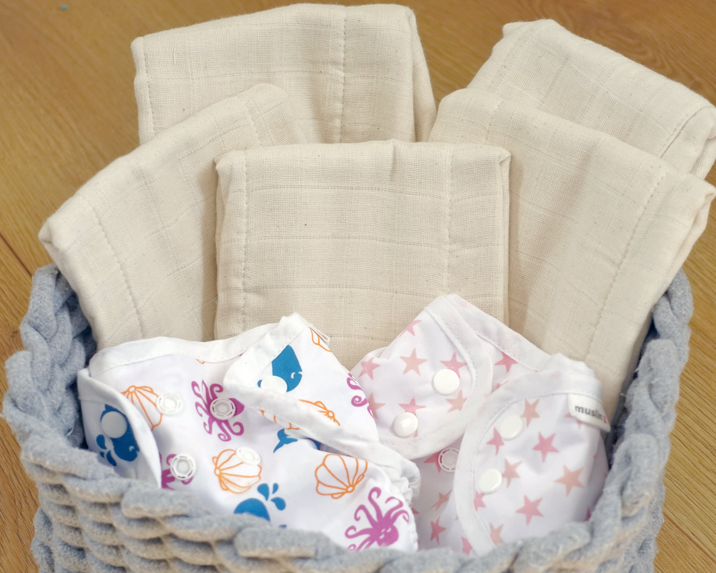 Basket of unbleached MuslinZ cotton prefolds with MuslinZ wraps
